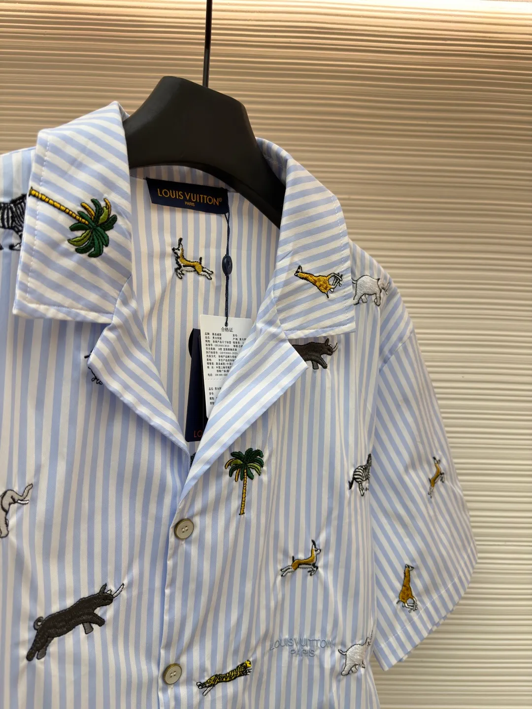 LOUIS VUITTON nostalgic style embroidered striped short-sleeved shirt with animals and plants ●Original version: Purchased and developed by 16815 ●Item number: 1682514-A65 ●Fabric: cotton fabric ●Technology: embroidery production ●Color: blue ●Version: fitted version ●Weight: about 220 grams ●Size: S-M-L-XL ●Description: This LOUIS VUITTON striped animal embroidery short-sleeved shirt is made of high-count pure cotton poplin fabric. After pre-washing process, it feels smooth and breathable. It has both drape and stiffness, and is not easy to wrinkle and deform. The blue and white vertical stripes on the body are woven with yarn-dyed technology, and the texture is clear and does not fade. The animal and coconut tree patterns are presented with sophisticated embroidery technology. The embroidery threads are full of color and the stitches are dense. The patterns are three-dimensional and vivid, forming a rich visual hierarchy with the stripe base. The shirt has a Cuban collar style, with smooth necklines, custom mother-of-pearl buttons at the placket, and a warm texture. The overall shape is loose, the shoulder joints are straight and fine, the cuffs are cuffed with exquisite craftsmanship, custom accessories and three logos are complete, and the details are full of luxury craftsmanship. It is suitable for casual vacations and daily outings, etc. The overall wiring is straight and delicate, the fabric is comfortable and soft, and the color is consistent without color difference. It can be matched with the same style to create a fashionable look and control various occasions. Customized accessories, complete with three standards, same style for men and women!